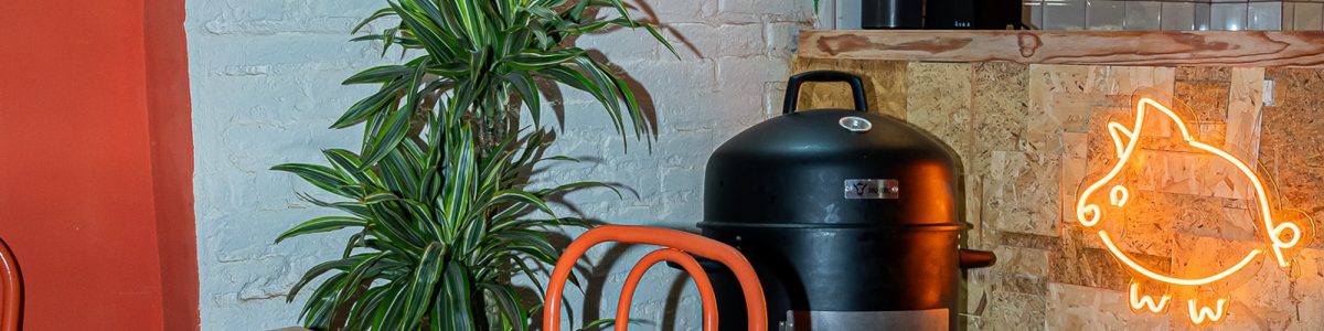Interior de ComePorketa en el Eixample de Barcelona: ahumador a la vista, sillas naranjas y neón del cerdito, sala de fast casual