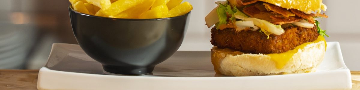 Porky Burger con pan brioche y queso cheddar junto a bowl de patatas fritas en ComePorketa — mejor restaurante de burgers cerca de la Sagrada Família Barcelona